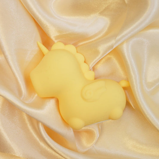 Top view of the yellow Unihorn Bean Blossom clitoral stimulator resting on soft yellow satin fabric | Flirty bay adult store and lingerie store
