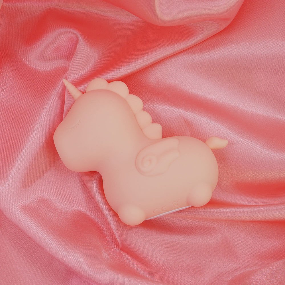 Top view of the Unihorn Heart Throb pulsing clitoral stimulator on soft pink fabric | Flirty Bay adult store and lingerie store