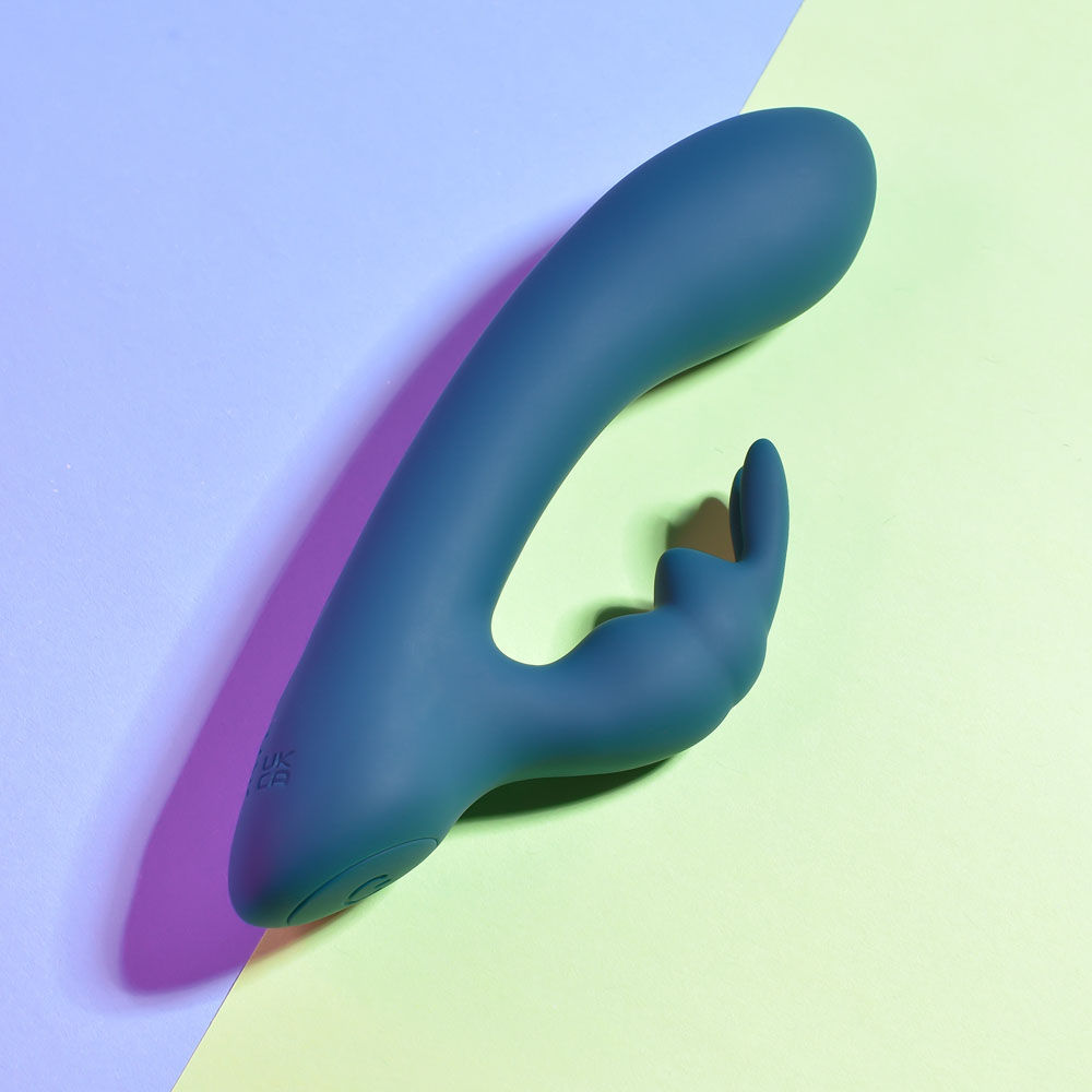 Top Side view of the packaging and teal Playboy Pleasure Lil Rabbit vibrator on a green and blue background | Flirty Bay adult store and lingerie store