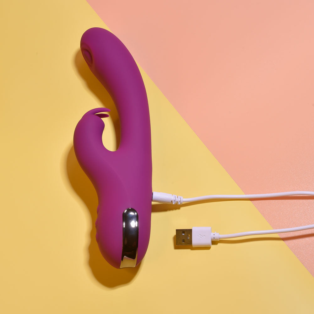 Top Side view of the Playboy Pleasure Thumpur thumping rabbit vibrator on a purple and yellow background, with the magnetic charger | Flirty bay adult store and lingerie store
