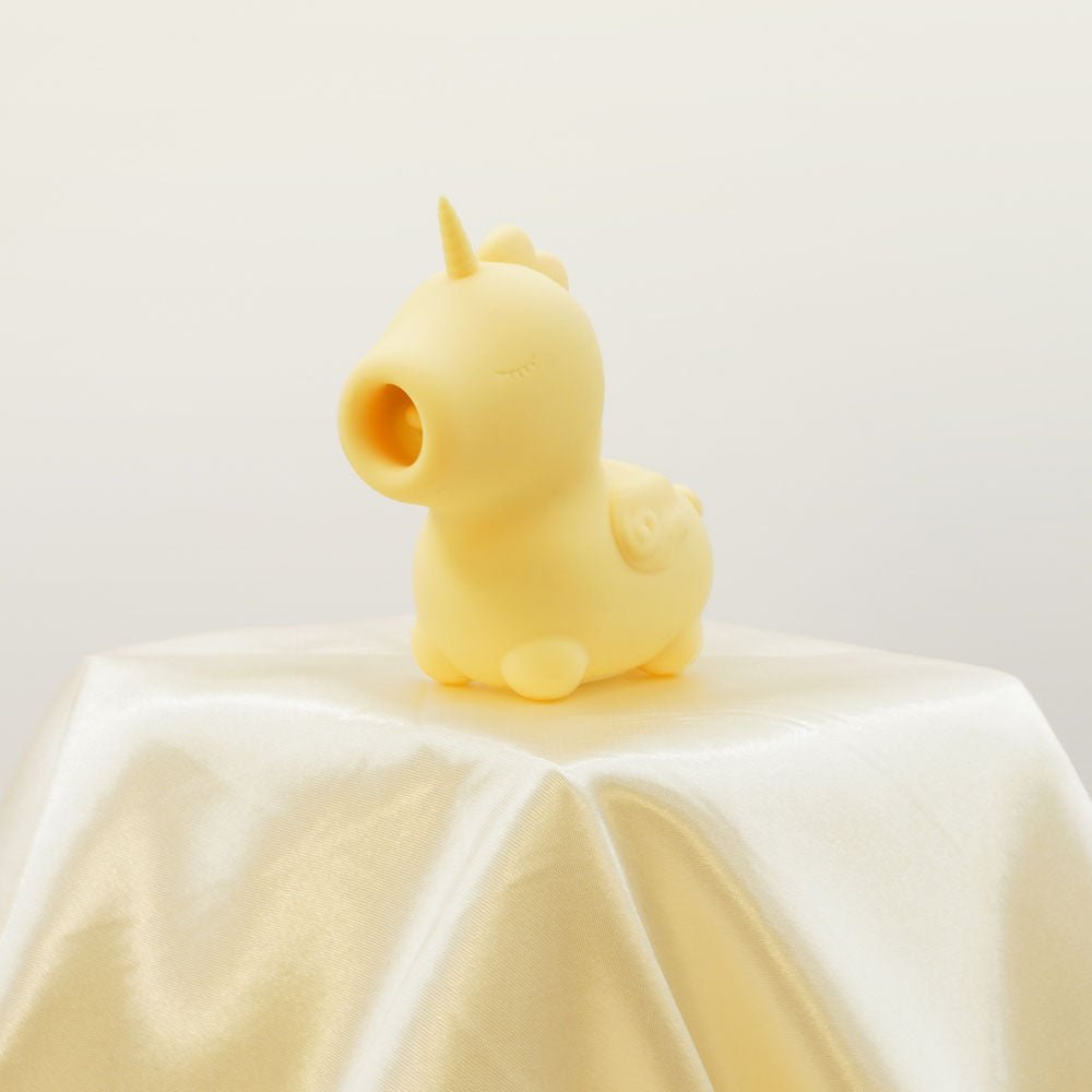 Side view of the yellow Unihorn Bean Blossom clitoral stimulator resting on soft yellow satin fabric | Flirty bay adult store and lingerie