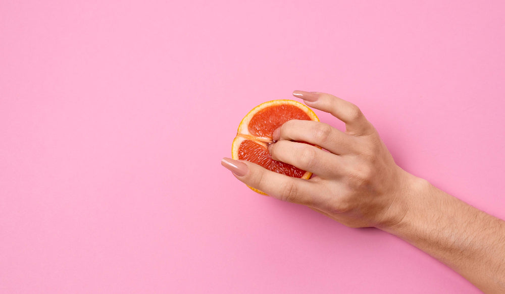 image of womans hand touching blood orange with fingers