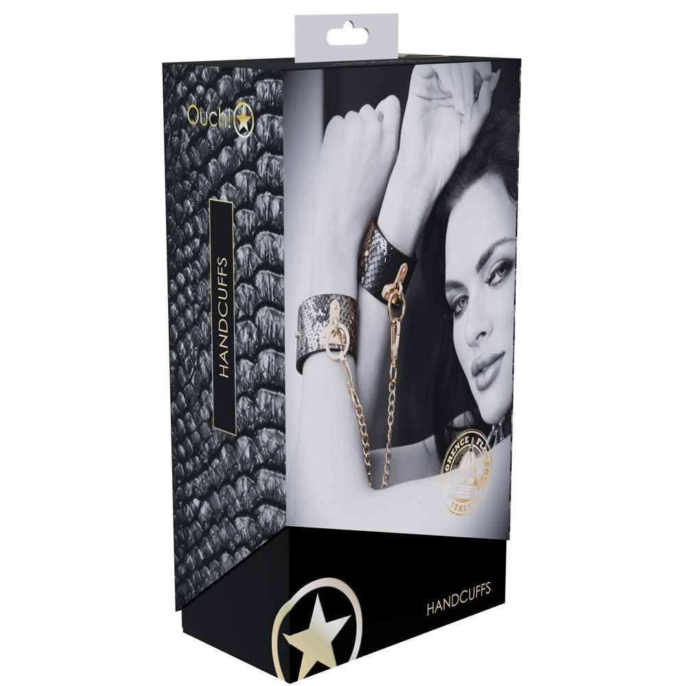 Elegant black faux leather bondage sex handcuffs with gold chain and snakeskin pattern, perfect for stylish bedroom restraint play, box view | Flirty Bay online adult store, adult toys and lingerie