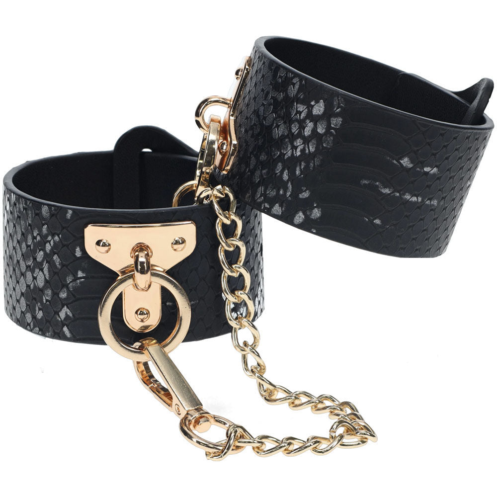 Elegant black faux leather bondage sex handcuffs with gold chain and snakeskin pattern, perfect for stylish bedroom restraint play, front view | Flirty Bay online adult store, adult toys and lingerie