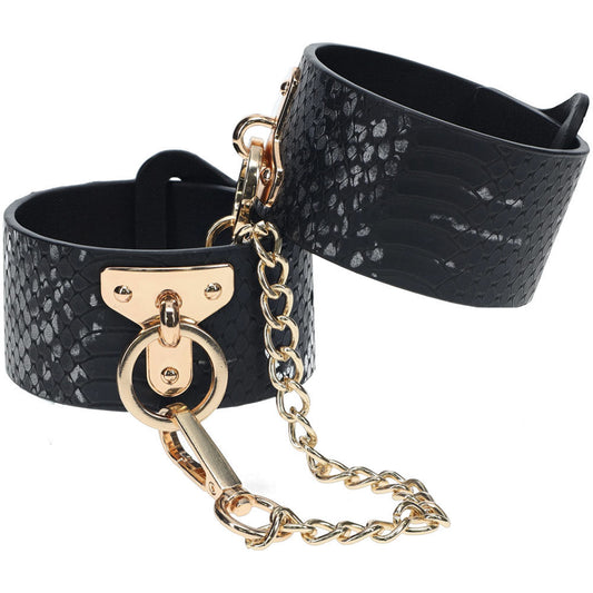 Elegant black faux leather bondage sex handcuffs with gold chain and snakeskin pattern, perfect for stylish bedroom restraint play, front view | Flirty Bay online adult store, adult toys and lingerie