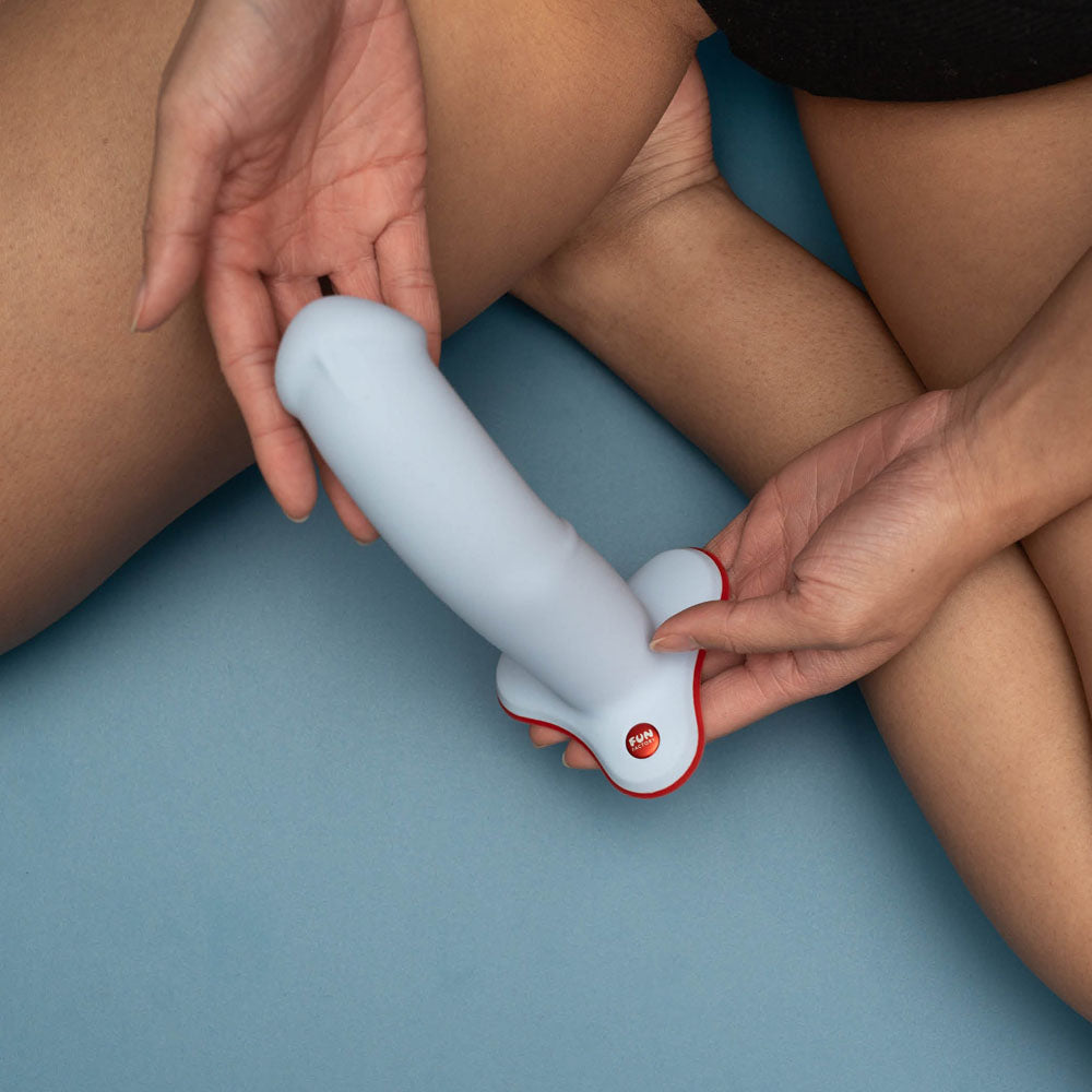 Top view of the Fun Factory The Boss Stub Dove Dildo 7" held in hand on blue background | Flirty Bay, sex toys Australia