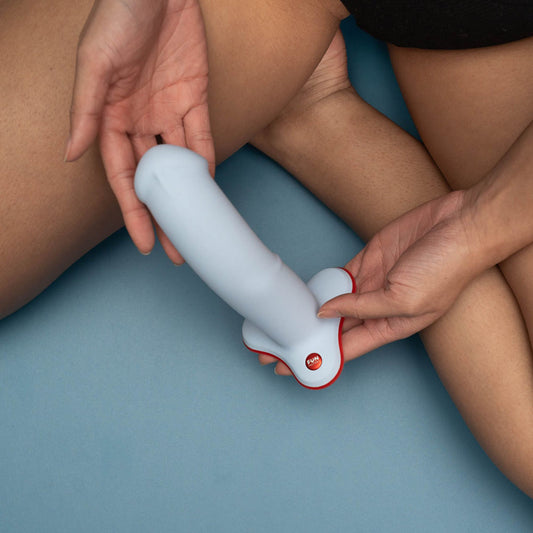 Top view of the Fun Factory The Boss Stub Dove Dildo 7" held in hand on blue background | Flirty Bay, sex toys Australia