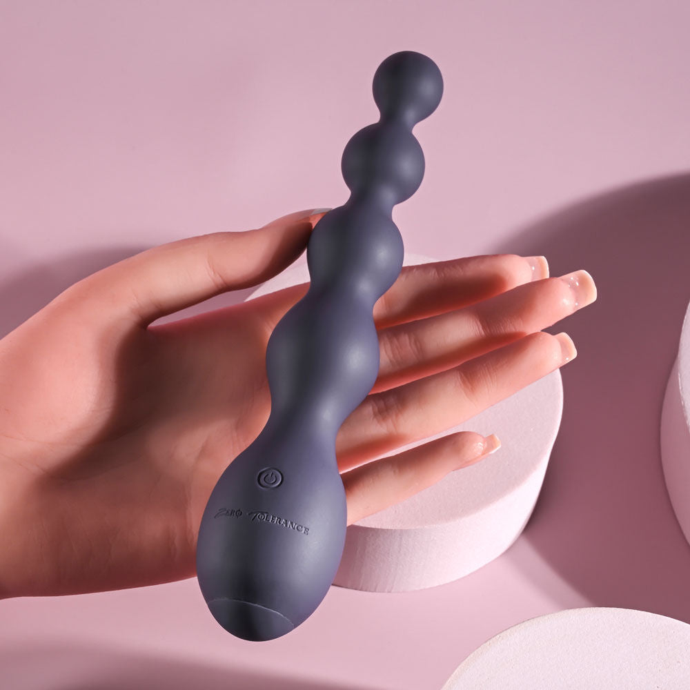 Zero Tolerance Rumpy Bumpy vibrating anal beads held in hand, demonstrating size and flexibility against a light purple backdrop | Flirty Bay, anal plug adult store Australia