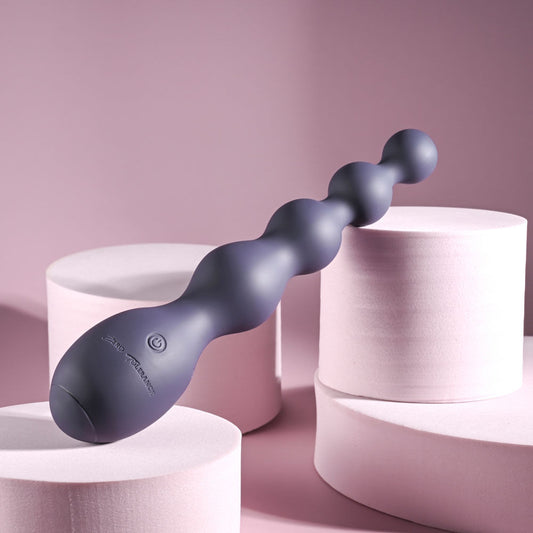Side view of Zero Tolerance Rumpy Bumpy vibrating anal beads highlighting the on/off button on its ergonomic base in a light purple setting | Flirty Bay, anal plug adult store Australia