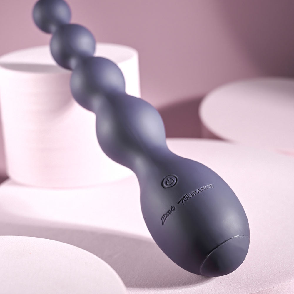 Top Side view of Zero Tolerance Rumpy Bumpy vibrating anal beads highlighting the on/off button on its ergonomic base in a light purple setting | Flirty Bay, anal plug adult store Australia